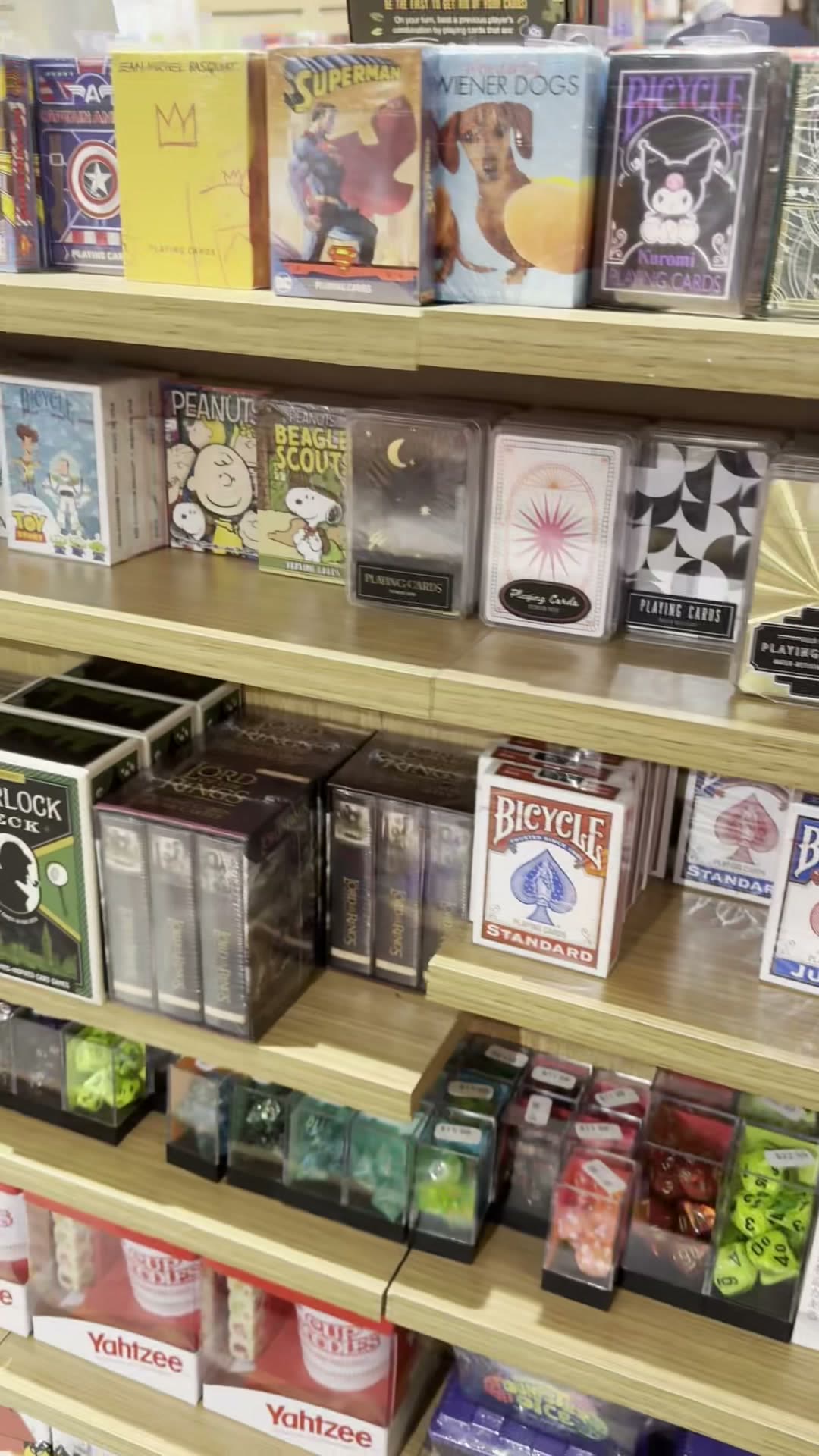 A shelf of themed playing cards including Superman, Wiener Dogs, Kuromi, and Lord of the Rings